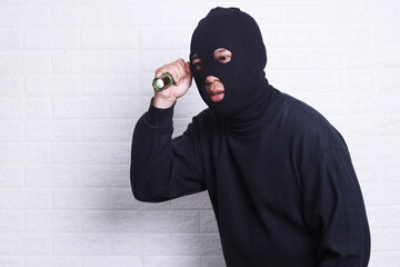 Disguised thief with robbery mask holding a flashlight over white background.