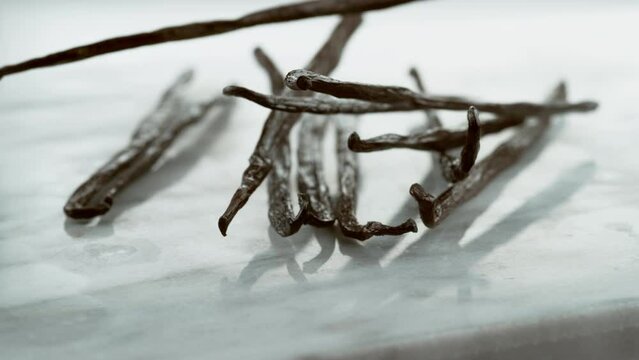 Vanilla beans falling on white background slow motion