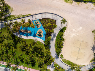 Beach boardwalk next to park with playground and palm trees