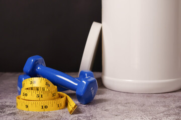 Whey protein powder, shaker, measuring tape and dumbbells on black background and copy space