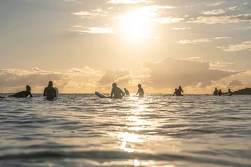Crédence en verre imprimé Coucher de soleil sur la plage silhouette of a group of surfers floating in the ocean