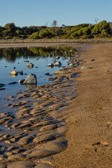 Water trapped on a beach at low tide with rocks showing.