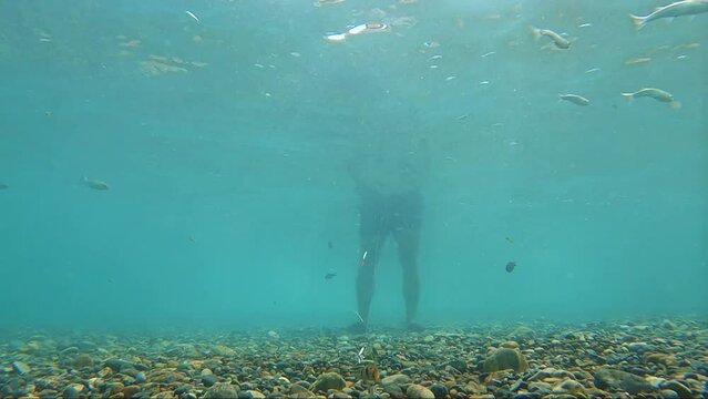 Underwater view of fish hook by fisherman fishing on standing at the seashore mediterranean sea.