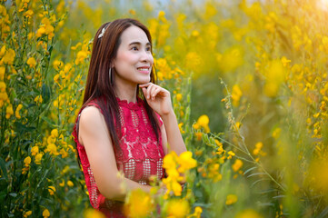 Asian woman standing among yellow flowers