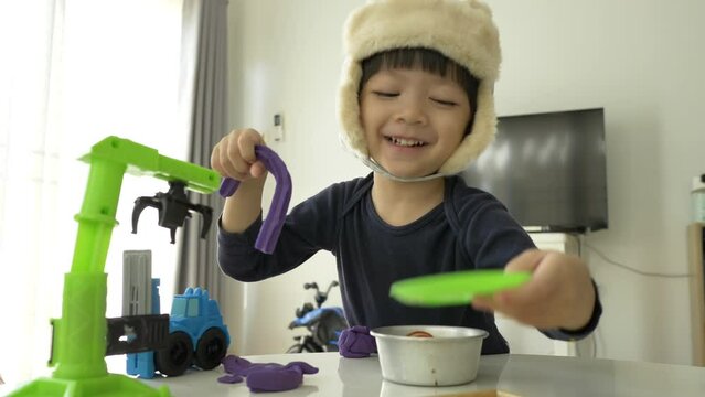 little boy wear hat playing plasticine dough and construction set, slow motion scene