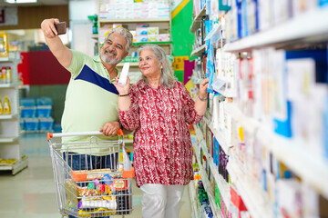 Senior couple talking on video call,using smartphone while shopping at grocery shop.