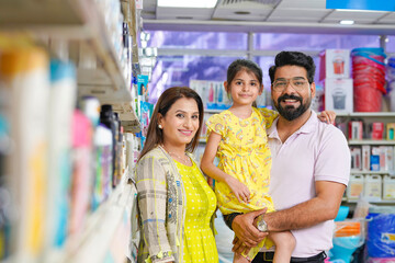 Happy indian couple standing with his daughter at grocery shop.