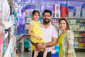 Happy indian couple standing with his daughter at grocery shop.