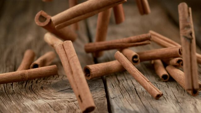 Cinnamon sticks falling on wood in slow motion