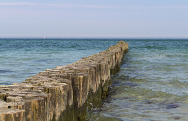 Fototapeta premium Wooden breakwater in the blue turquoise Baltic Sea with horizon and calm water. Diagonal.