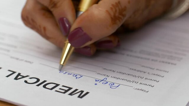 Closeup shot of a female signing medical indemnification form. A young Indian woman filling a form - medical insurance / medical loan  healthcare and medical