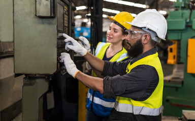 Beardman factory engineer worker checking main switch in industrial warehouse with woman teammates