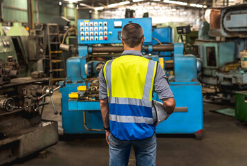 Fototapeta na wymiar Back view Engineer factory man looking at heavy machinery in industrial factory