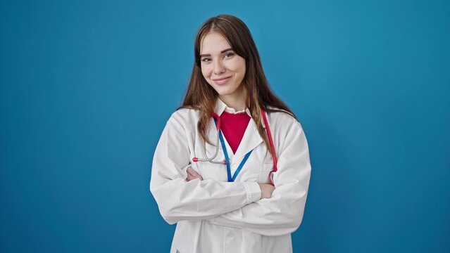 Young hispanic woman doctor smiling confident standing with arms crossed gesture over isolated blue background