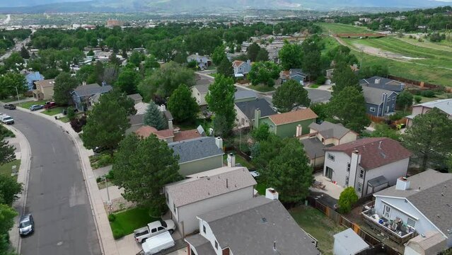 Housing neighborhood in Colorado. Aerial tilt up reveals Rocky Mountains. Drone establishing shot.