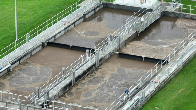 Sewage in filtration tanks at wastewater treatment plant in USA. Aerial establishing shot of public water works.