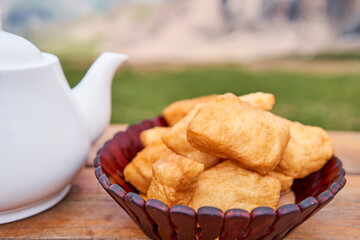 Teapot with tea and delicious National Kazakh pastries baursak. Street cafe in the highlands with a view of the mountains.. Fry dough in boiling oil in a frying pan.
