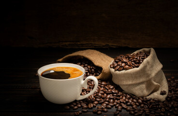 Black coffee or hot tea in a cappuccino espresso cup, breakfast food with coffee beans on a wooden table Isolated on a dark background, top view