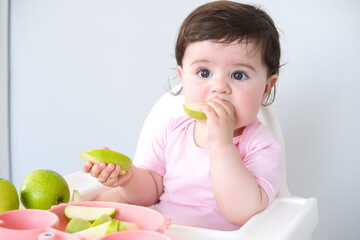 baby eating apple sitting in a high chair. weaning