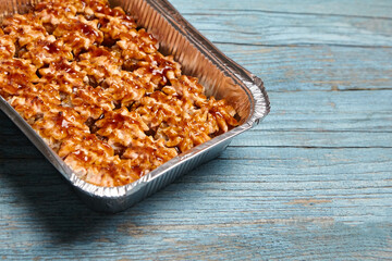 Baked sushi rolls in a baking dish on blue wooden background closeup, copy space. Beautiful accent on baked sushi