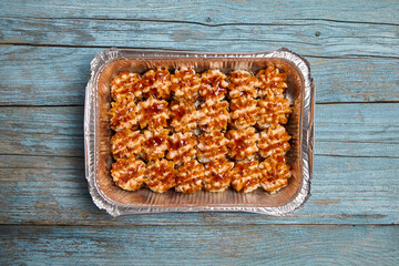 Baked sushi rolls in a baking dish on blue wooden background, top view. Hot sushi rolls with different kind of fish and fillings. Golden-brown baked sushi delights