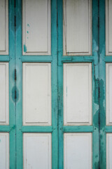 The door of an ancient house is made of wooden panels connected to hinges, painted in green.