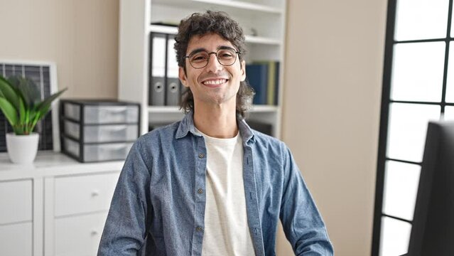 Young hispanic man business worker looking clock smiling at office