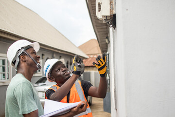 two african electricians working together at a home