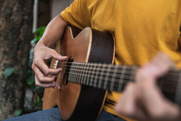 Fototapeta na wymiar Close up man playing guitar on park bench