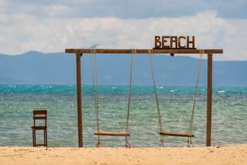 Wooden two swings and chair on peaceful beach background on tropical island of Koh Phangan, Thailand, relax by the sea, summer holiday destination