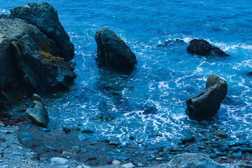 Deep blue ocean with large black rocks