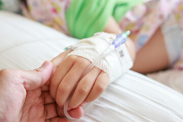 Obraz na płótnie Canvas Mother holding child hand with saline IV solution in hospital