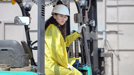 Black-haired woman sits in excavator for trash transporting at big waste sorting plant. Female manager checks durability of apparatus in factory