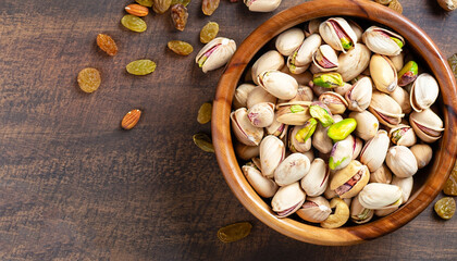 Pistachios nuts in wooden bowl. Food mix background, top view, copy space, banner. Assortment of nuts - cashew, hazelnuts, almonds, walnuts, pistachio, pecans, pine nuts, peanut, raisins.