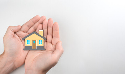 hands holding house icon on paper, family home, homeless shelter, family day care, housing mortgage crisis. copy space. white background