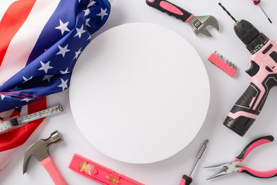 Recognizing contributions of women in labor on American Labor Day. Top view picture showcasing American flag and construction tools on white isolated backdrop, allowing for advert or text placement