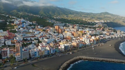 Fototapeta na wymiar Flying over Santa Cruz de La Palma - capital of La Palma island, Canary. Aerial shot of coastline, colored houses and green mountains in the background on the island of La Palma