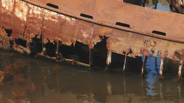 Old Rusty Boat Shipwreck in Water with Reflection, Medium shot, Panning