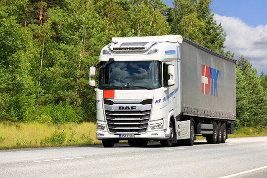 New, white DAF XG 480 truck pulls semi trailer on highway.