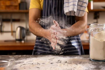 Midsection indian man in apron preparing bread dough in sunny kitchen at home