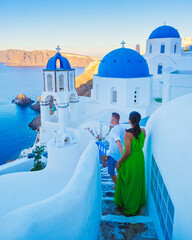 A couple walking at the village of Oia Santorini Greece, men and women visit the whitewashed Greek village of Oia during summer vacation - obrazy, fototapety, plakaty