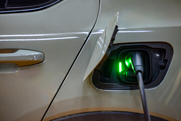 Fototapeta premium EV charging an electric car.Power supply for electric car charging. Socket for electric car battery charger. EV car charging station. Nature energy, Clean energy, Green eco concept. Plugging in cable.