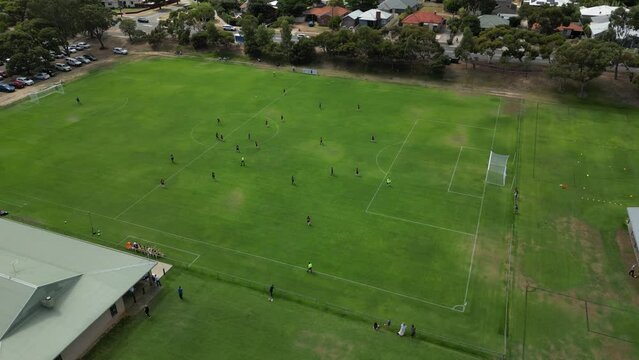 Aerial flight over soccer stadium during match and goalkeeper kicking the ball - Cloudy day in Perth, Western Australia