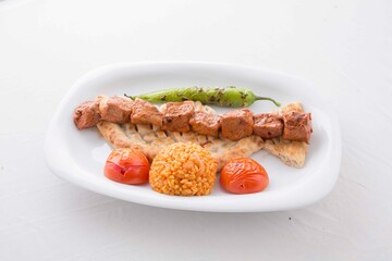 Barbecued red meat served with tomato, pita, pepper and bulgur pilaf during service