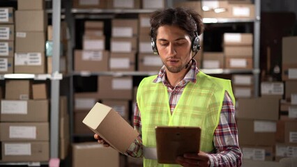 Warehouse man staff using digital tablet and talking to customer with headset working in distribution factory. Support operator working for online shopping.