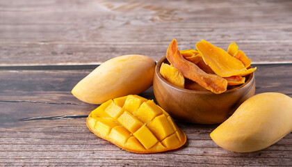 Dried mango in wooden bowl and fresh mango fruit on wood textured background. Copy space....