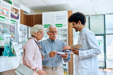 Obraz premium Senior man and his wife talk to pharmacist while buying medicine in pharmacy,