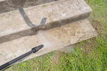 Cleaning of old dirty concrete steps with high-pressure washer