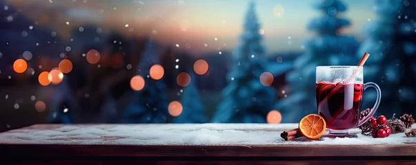 Fotobehang A glass of mulled red wine with cinnamon on old rustic wooden plank against blue background with winter landscape © Александр Марченко