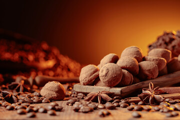 Chocolate truffles with cinnamon, anise, and coffee beans on a wooden table.